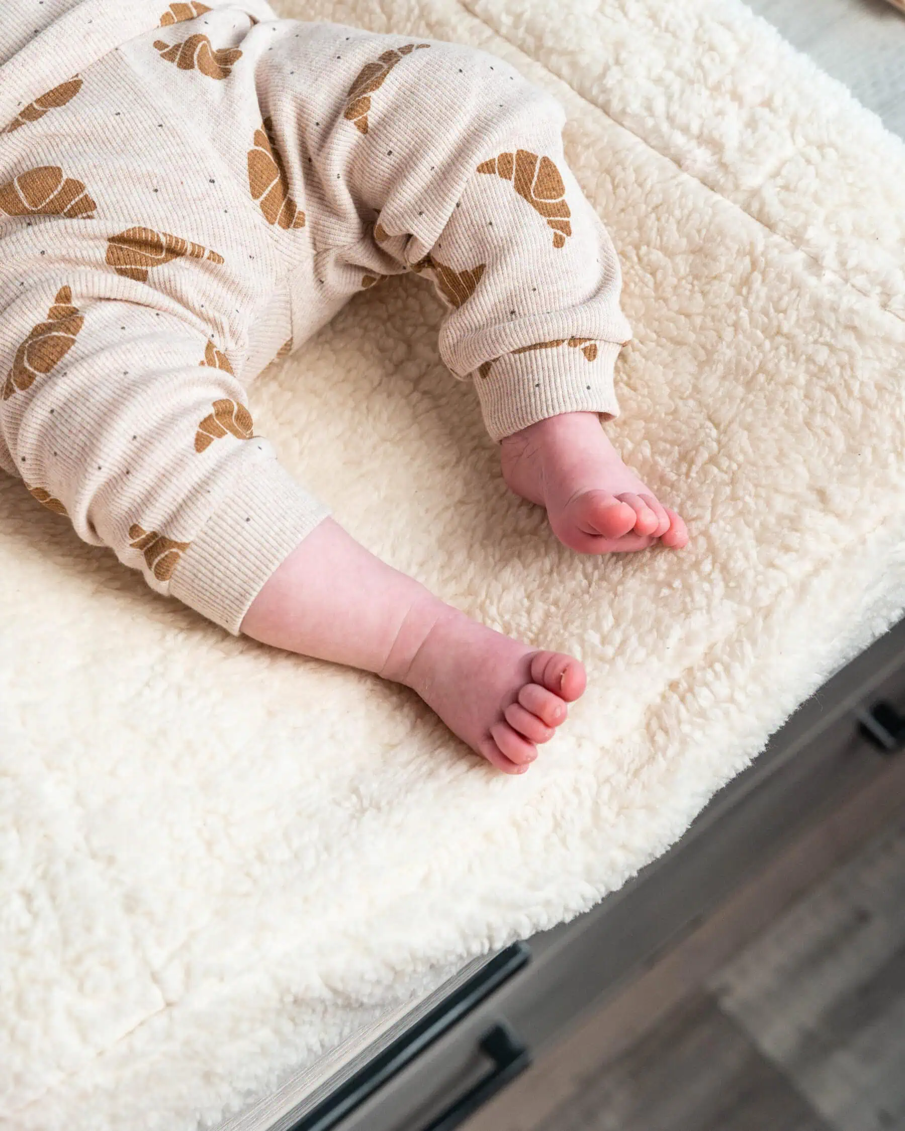Close up of a baby resting on a plush cream-colored sherpa changing pad